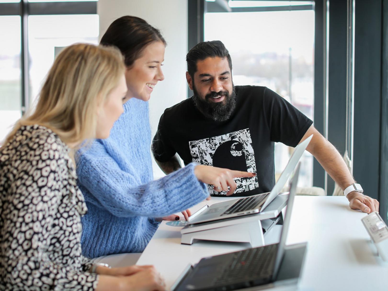 Image of three colleagues around a computer