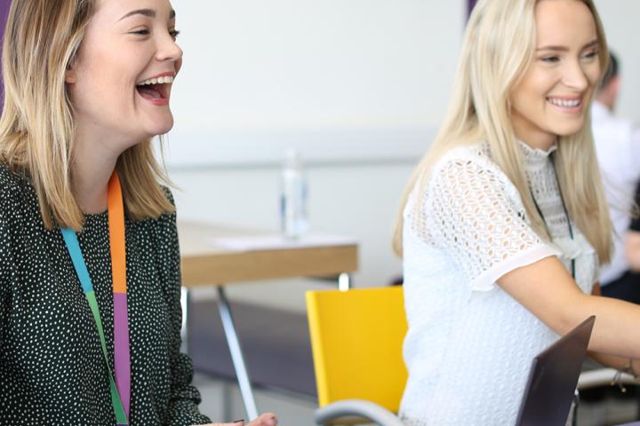 Two female colleagues laughing at a desk